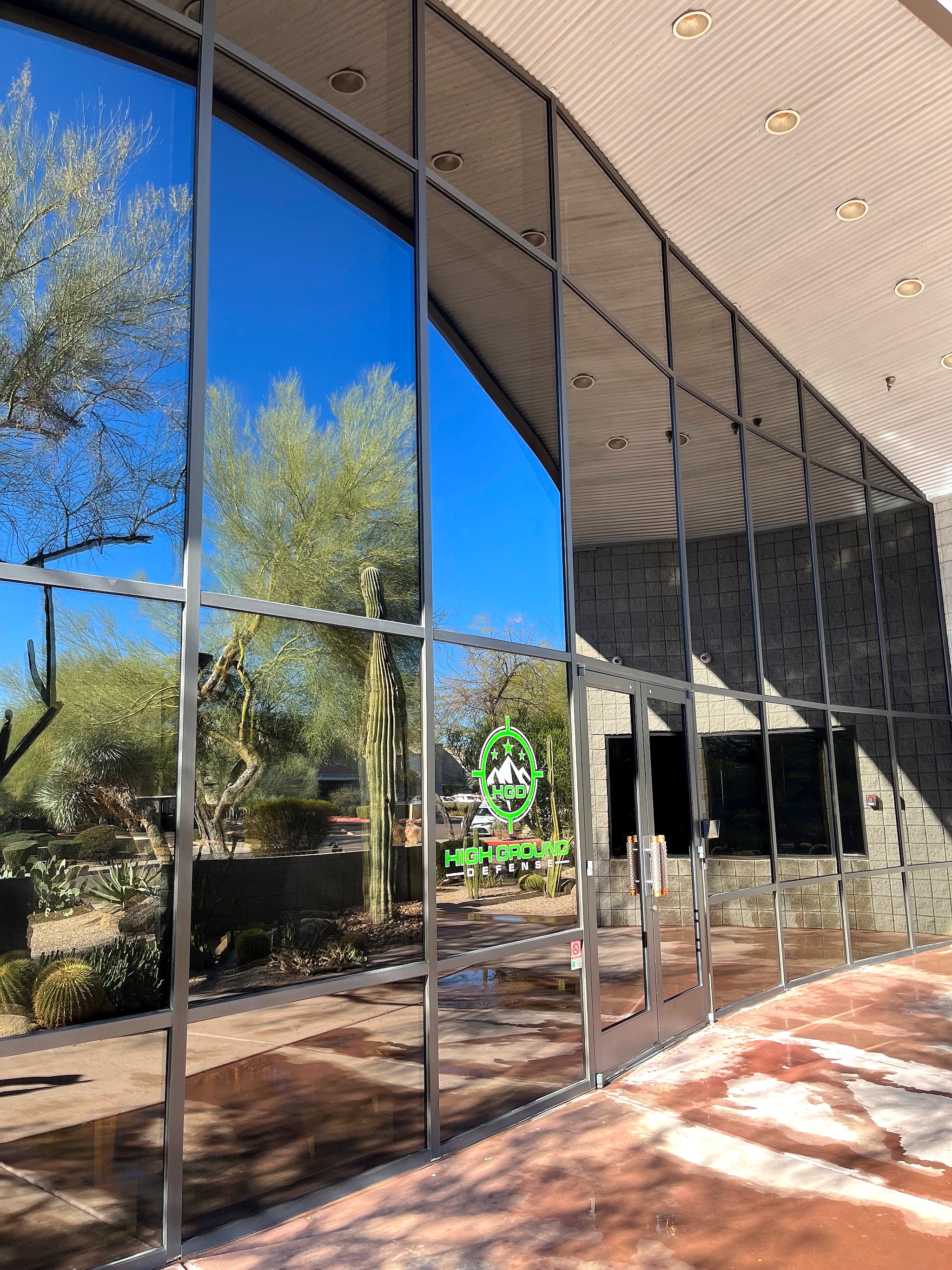 Storefront glass reflecting desert landscaping and blue sky